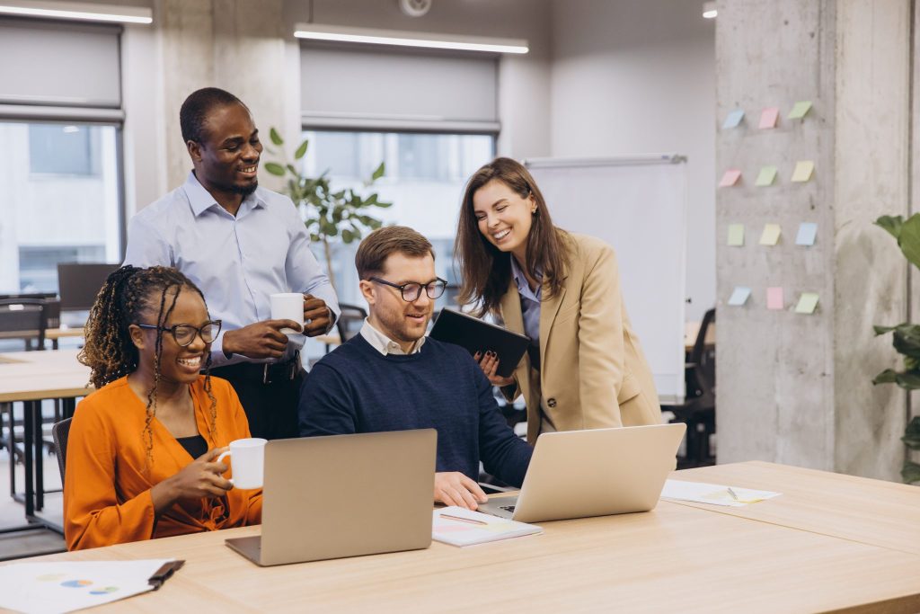 Colleagues around a laptop at work smiling